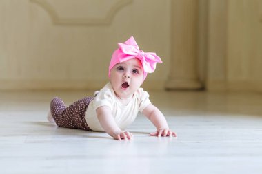 Ev ya da stüdyo iç yerdeki küçük bebek şaşırttı. Parlak bir gül yay üzerinde bir kafa ile şirin güzel 6 ay kız. Açık renkli