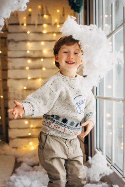 Sevimli küçük çocuğa Noel ışıkları arka plan ile sahte kar oynarken