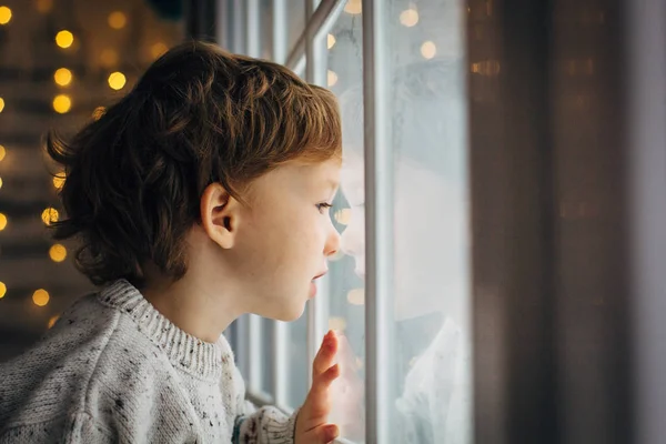 Niño esperando a Santa Claus. Lindo niño rizado sentado cerca de la ventana —  Fotos de Stock