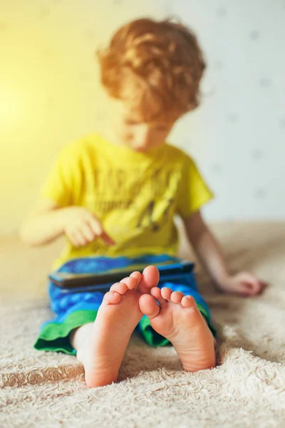 Kleiner süßer Junge in grünem T-Shirt, der auf einem Tablet Spiele spielt und sich Cartoons ansieht. Suchtkonzept — Stockfoto