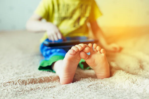 Niño pequeño usando la tableta en una cama — Foto de Stock