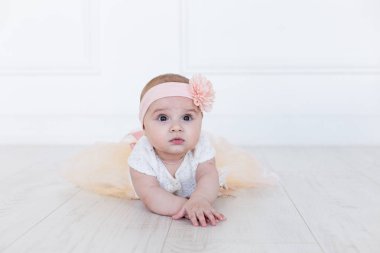 A baby girl is crawling along the floor with an inquisitive and wondering look on her face. Horizontal shot. clipart