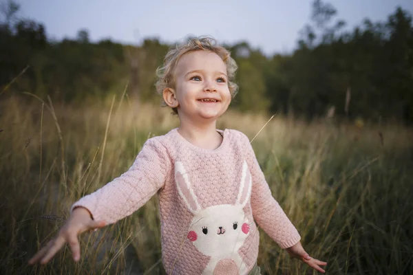 かわいい巻き髪金髪少女 ピンクのセーターの幼児 屋外の赤ちゃんの肖像画 — ストック写真