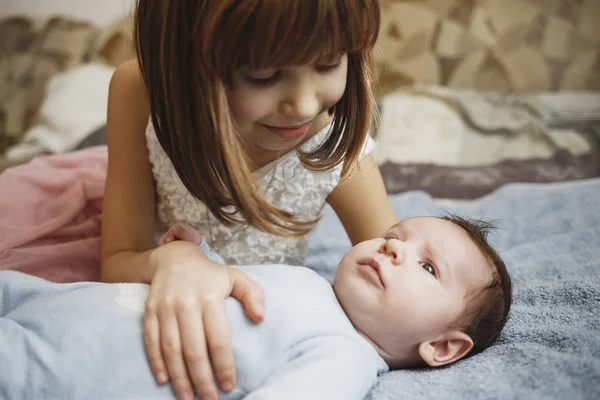 Χαριτωμένο κορίτσι ευτυχισμένη κρατώντας το νεογέννητο μωρό της αδελφό. Γκρι φόντο. Όμορφο αγοράκι με μπλε ρούχα — Φωτογραφία Αρχείου