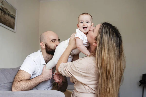 Familia feliz, madre y padre jugando con una hija pequeña en casa. Copiar espacio. Padres besando bebé, linda chica sonriendo — Foto de Stock