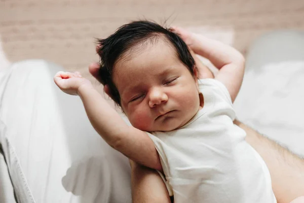 Bebé recién nacido dormido en las manos del padre. Bebé con cabello oscuro — Foto de Stock