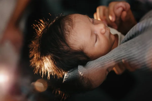 Retrato de un bebé recién nacido: Un bebé recién nacido está durmiendo en las manos. Ella tiene el pelo negro . — Foto de Stock