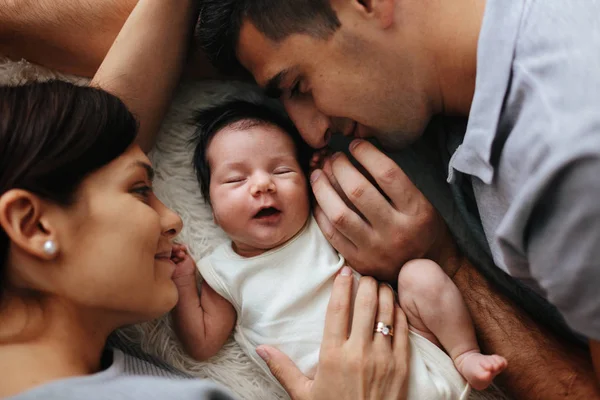 Primer plano de padres felices sosteniendo a su bebé recién nacido. Familia en la cama — Foto de Stock