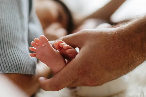 Padres sosteniendo en las manos los pies del bebé recién nacido. — Foto de Stock