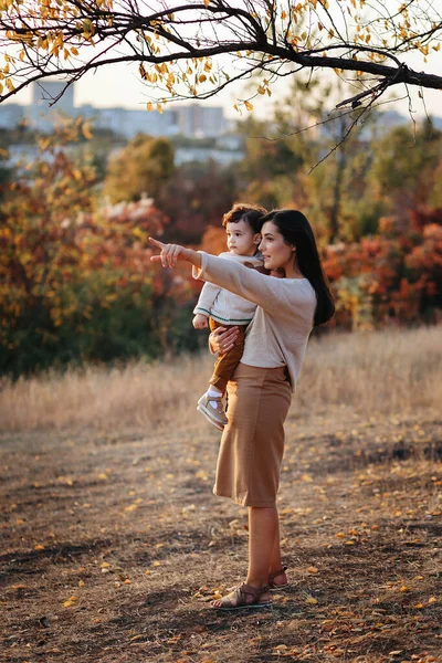Joven madre caucásica con un niño niño niño bebé en sus manos caminando y sonriendo en el otoño en la naturaleza —  Fotos de Stock