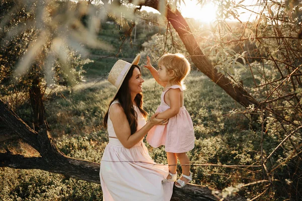 Beautiful Mother And her little daughter outdoors. Nature. Beauty Mum and her Child playing in Park together. Outdoor Portrait of happy family. Happy Mothers Day Joy. Mom and Baby. Woman in straw hat — Stock Photo, Image