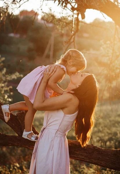 Beautiful Mother And Baby outdoors. Nature. Beauty Mum and her Child playing in Park together. Outdoor Portrait of happy family. Mom and Baby portrait. Woman kissing her daughter. Suset time — Stock Photo, Image