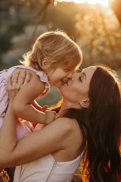 Hermosa madre y bebé al aire libre. Naturaleza. Beauty Mum y su hijo jugando juntos en Park. Retrato al aire libre de familia feliz. Retrato de mamá y bebé. Mujer besando a su hija. Tiempo de suspensión — Foto de Stock