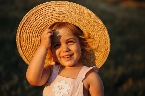 Una chica con sombrero de paja en el campo. Retrato de una chica sonriente. El bebé se ríe. Adorable niña —  Fotos de Stock