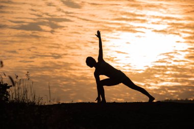 Siluet Asya kadın yoga günbatımı üzerinde. Günbatımı gökyüzü arka plan
