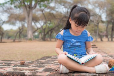 Küçük kız kitap okuyor.