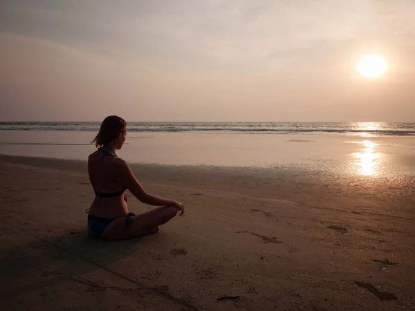Девушка Сидит Песчаном Пляже Моря Напротив Заходящего Солнца — стоковое фото