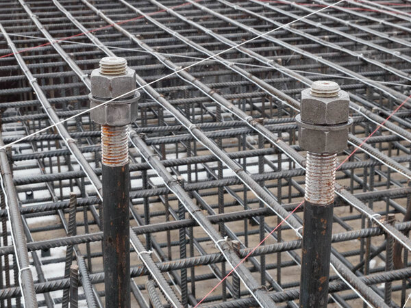 Two steel anchor bolts with screw nuts and steel grid on tower crane footing reinforcement