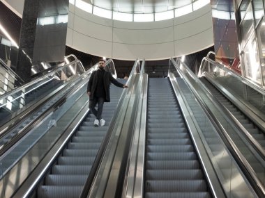 Yün ceket giymiş yakışıklı sakallı adam Metro yürüyen merdiven üzerinde duruyor