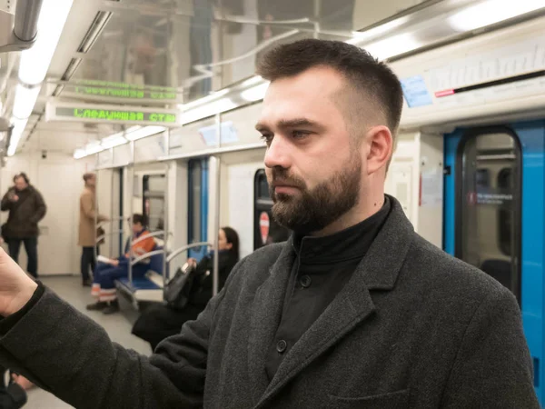 Handsome bearded man dressed in wool coat stands in metro carriage — Stock Photo, Image