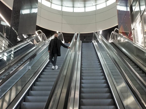 Szép szakállas férfi öltözött gyapjú kabát áll a metró mozgólépcső — Stock Fotó