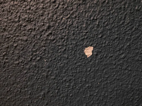 Black plastered textured wall with cracked missing spot — Stock Photo, Image