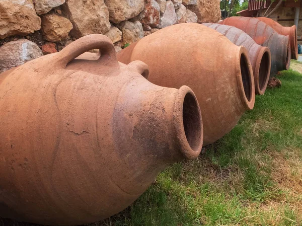 Amphoras céramiques anciennes sur la pelouse verte contre le mur de pierre — Photo