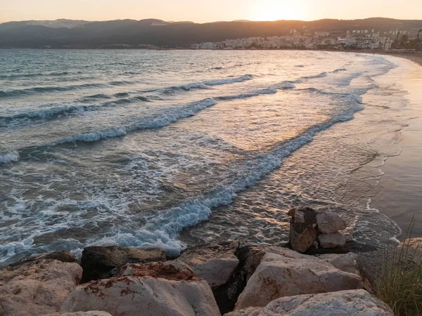 Salpicando olas espumosas del mar golpean la playa de guijarros en los rayos del atardecer. Tasucu, Silifke, Provincia de Mersin, Turquía — Foto de Stock