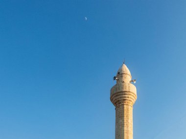 Akşam mavi gökyüzü ve ay karşısında cami minaresi