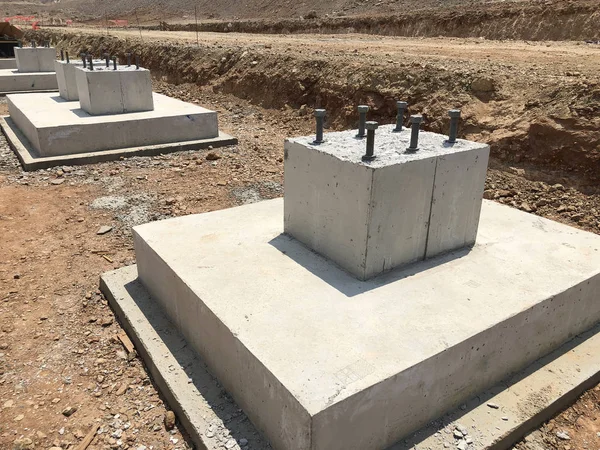 Fila de cimientos de hormigón armado con pernos de anclaje metálicos diseñados para la instalación de columnas metálicas. Fundamentos del almacén en el sitio de construcción — Foto de Stock