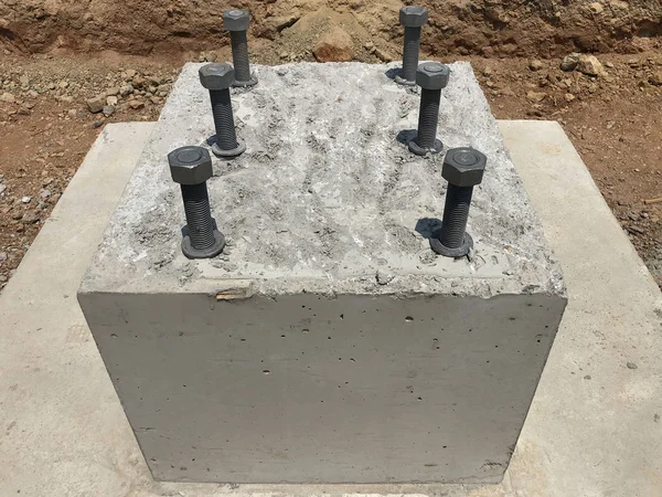 Reinforced concrete foundation with metal anchor bolts designed for the installation of metal columns. Foundation of warehouse on the construction site