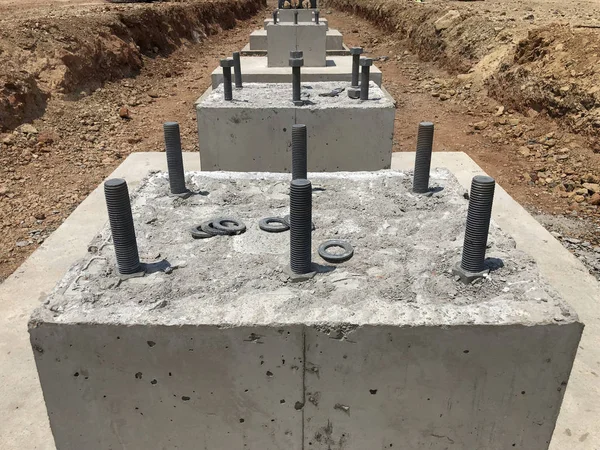 stock image Row of reinforced concrete foundations with metal anchor bolts designed for the installation of metal columns. Foundations of warehouse on the construction site