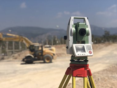 Arka planda bulanık makinelere karşı inşaat alanında jeodezik toplam istasyon