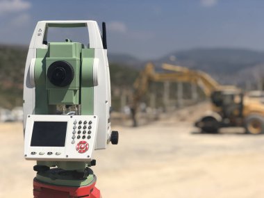 Arka planda bulanık makinelere karşı inşaat alanında jeodezik toplam istasyon