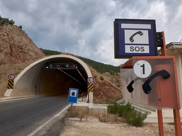 Cabina telefónica para llamadas de emergencia cerca de la entrada del túnel de la autopista. Infraestructuras de transporte y seguridad — Foto de Stock