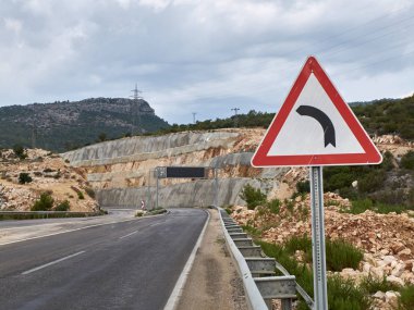 Yol işareti tehlikeli eğri ve boş afiş ile metal kemer ile Asfalt yol