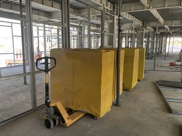 Bloques de cemento apilados envueltos en envases amarillos en el piso del edificio prefabricado de varios pisos —  Fotos de Stock