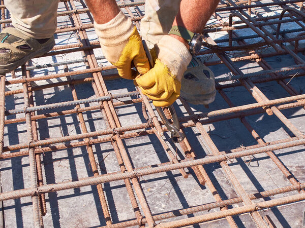 Hands of worker tying reinforcement rebars with haywire.