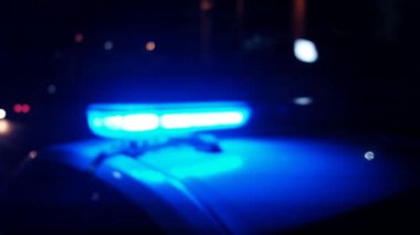 Polis arabasının gece lambaları yanıp sönüyor.