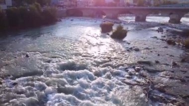 Günbatımında sığ ve eski Roma köprüsü olan geniş dağ nehri