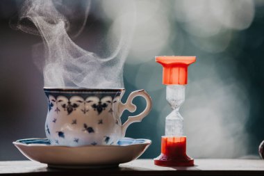 Çay vakti geldi. Temiz bir fincan çay mavi bir desen ve bir daire için tahta raylar üzerinde durmak. Hourglas
