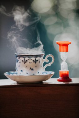 Çay vakti geldi. Temiz bir fincan çay mavi bir desen ve bir daire için tahta raylar üzerinde durmak. Hourglas