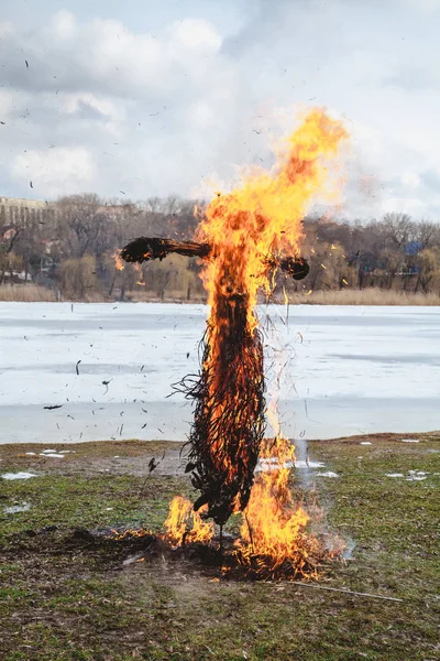 Slavic holiday of the end of winter. A large Shrovetide doll from straw burns on the river bank