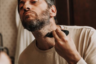 sakal düzeltici düzeltici. Adam bağımsız olarak gri sakalı bir makine ile keser