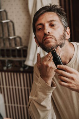 sakal düzeltici düzeltici. Adam bağımsız olarak gri sakalı bir makine ile keser