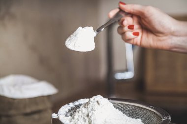 Metal bir elek ve bir kaşık un içinde bir el ile ben üzerinde un