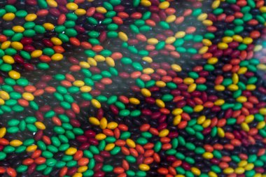 Arka plan. Küçük şeker drajelik parlak çiçek cam arkasında kaotik bir sırada yalan