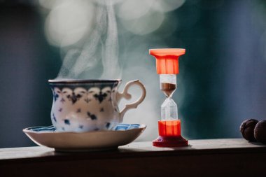 Çay vakti geldi. Temiz bir fincan çay mavi bir desen ve bir daire için tahta raylar üzerinde durmak. Hourglas