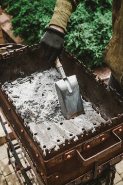 elinde siyah bir eldiven ile dar kıçına dövme metal mangal temizler