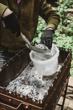 Mangal piknik sonra temizlik. Eller mangal dar bir kürek ile fırça. Külleri bir plastik containe kazıklı